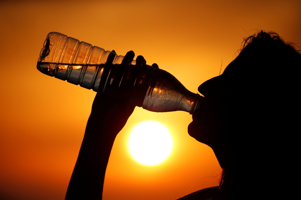 A woman drinks water during sunset as a heatwave hits France in Cagnicourt near Cambrai, France, June 25, 2019. Reuters / Pascal Rossignol
