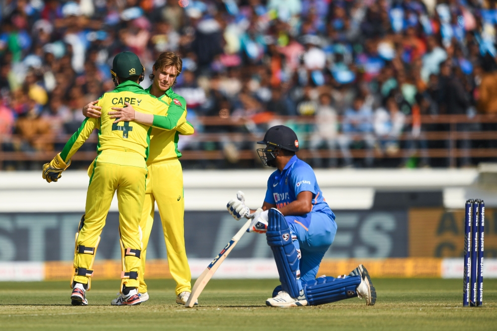 Australia's Adam Zampa (C) celebrates with teammate Alex Carey after dismissing India's Rohit Sharma during the second one day international (ODI) cricket match of a three-match series between India and Australia at Saurashtra Cricket Association Stadium 