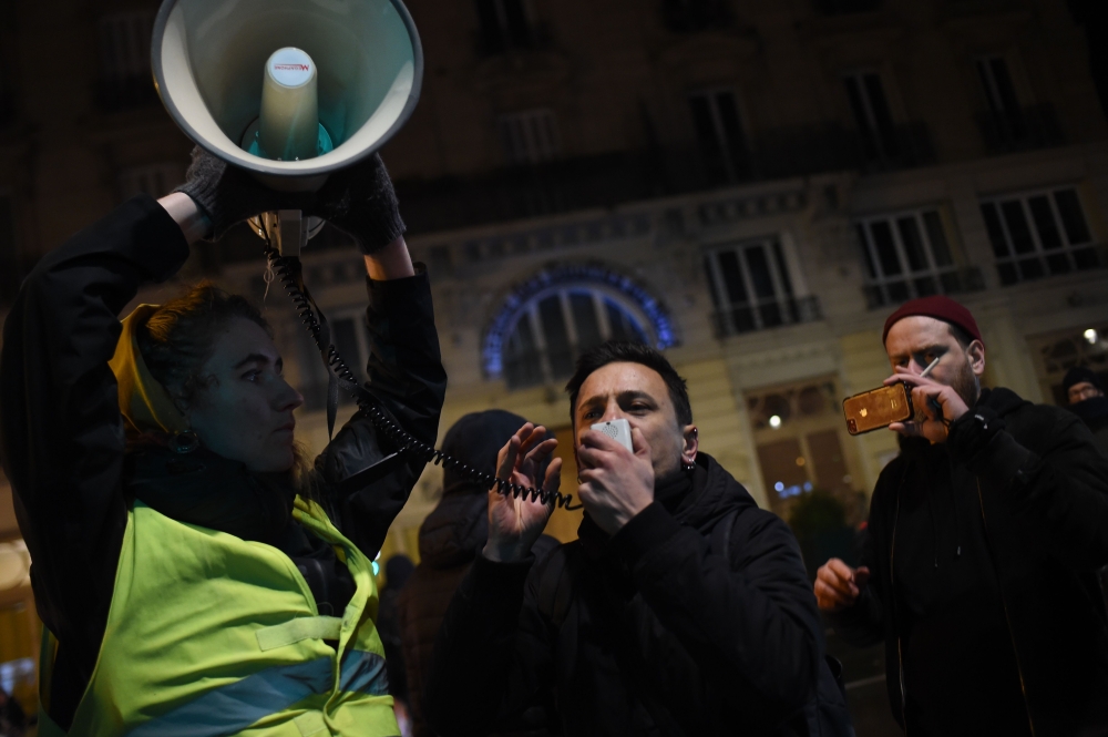 A protestor speaks in a megaphone during a demonstration in front of the Bouffes du Nord theatre in Paris on January 17, 2020, as French President attends a play. AFP / Lucas BARIOULET