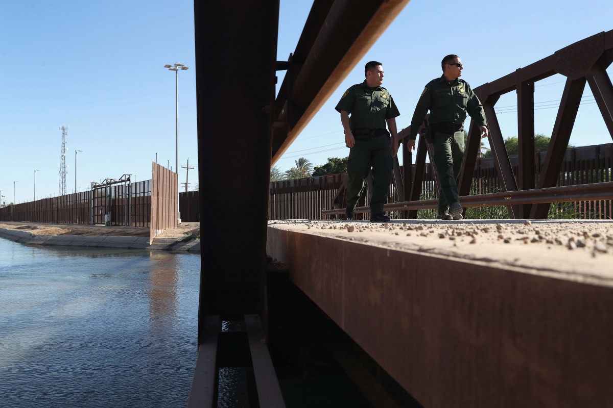 US Border Patrol agents walk over a canal of water flowing into Mexico at the US Mexico border fence on November 17, 2016 in San Luis, Arizona. John Moore / Getty Images / AFP