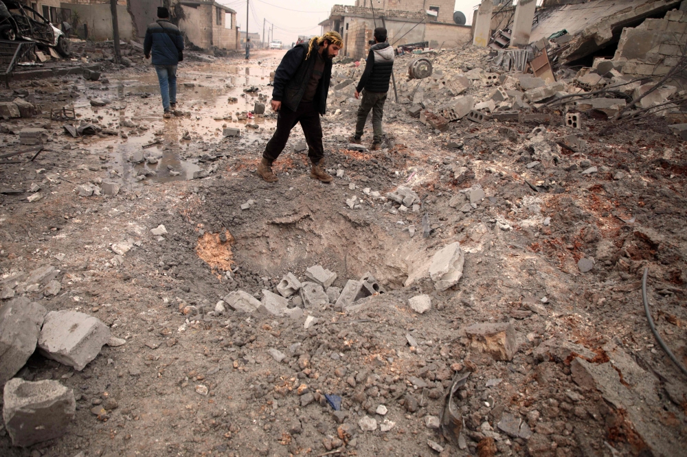 A Syrian man looks at a crater caused by a reported pro-regime bombardment in the village of Al-Jineh, in Aleppo's western countryside, on January 20, 2020. / AFP / Aaref WATAD