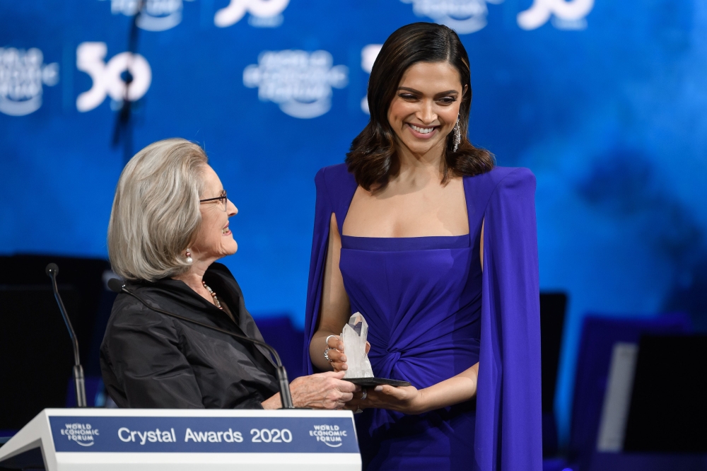 Indian actress Deepika Padukone (R) receive a trophy from Hilde Schwab, Chairwoman and Co-Founder of the World Economic Forum's World Arts Forum during the 