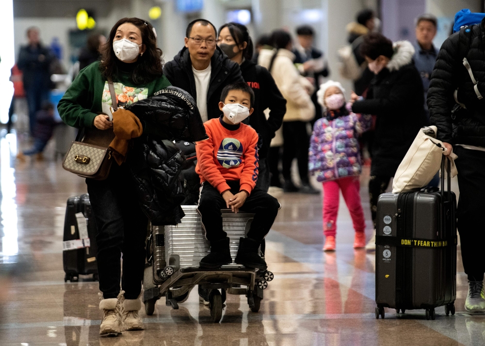 Travellers wearing protective masks arrive at the Beijing Capital Airport in Beijing on January 21, 2020. AFP / NOEL CELIS