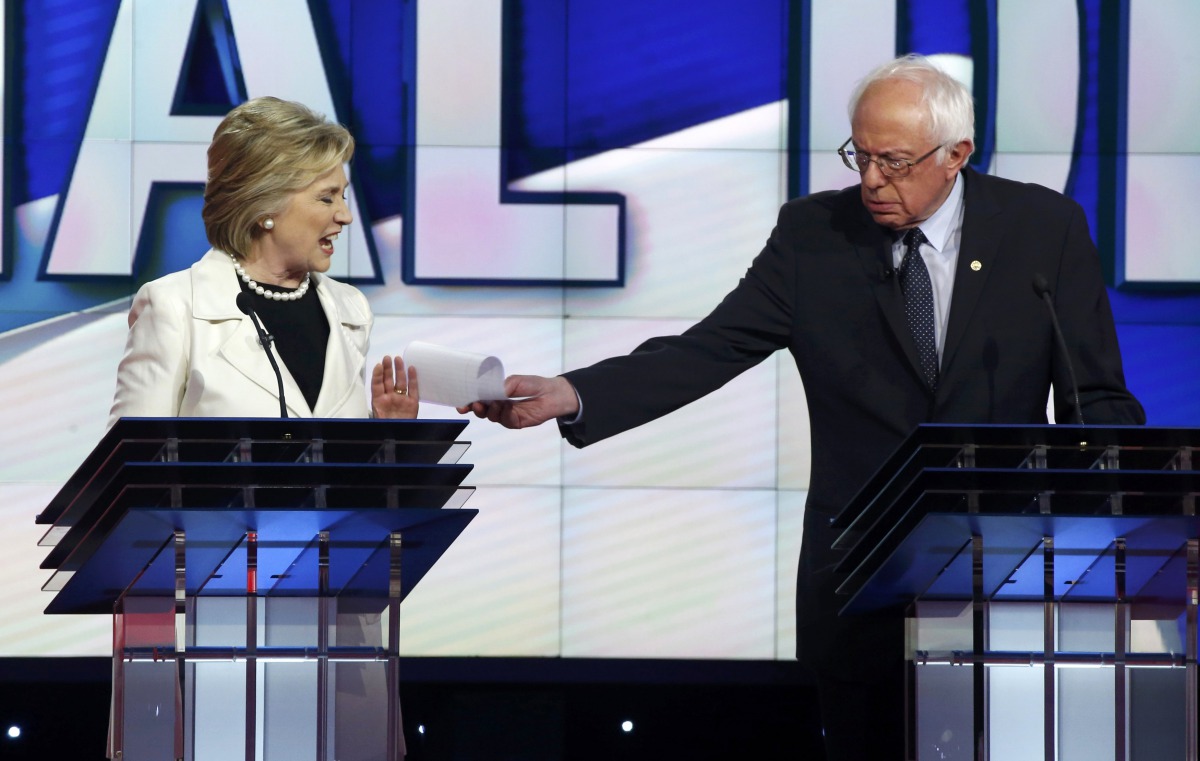 File photo: Hillary Clinton reacts as rival Bernie Sanders tries to hand her a piece of paper during a Democratic debate IN 2016. 