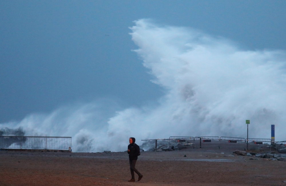 A man walks beside a sea wave during the storm 