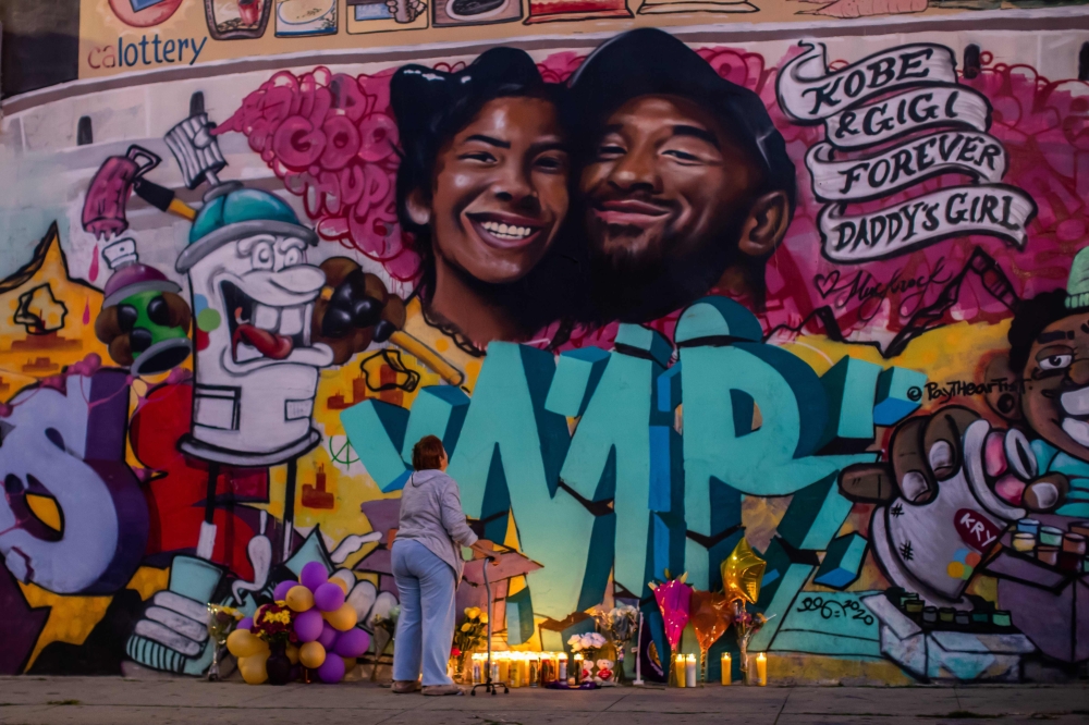 A woman looks at a mural by the artists Muck Rock and Mr79lts showing Kobe Bryant and his daughter Gianna Bryant, who were killed with seven others in a helicopter crash on January 26, in Los Angeles on January 27, 2020