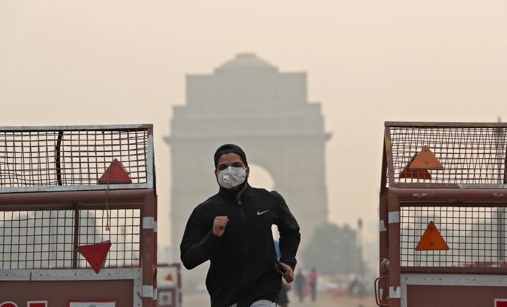 FILE PHOTO: A man wearing a mask runs past the India Gate on a smoggy morning in New Delhi, India, October 28, 2019 REUTERS/Adnan Abidi/File Photo 
