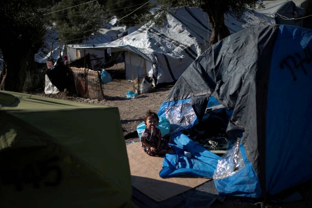 FILE PHOTO: child sits outside a tent at a makeshift camp for refugees and migrants next to the Moria camp on the island of Lesbos, Greece, September 1, 2019. REUTERS/Alkis Konstantinidis