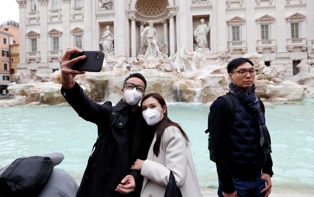 Tourists wearing protective masks take a selfie in front of ther Trevi's Fountain after two cases of coronavirus were confirmed in in the country, in Rome, Italy January 31, 2020. REUTERS/Remo Casilli