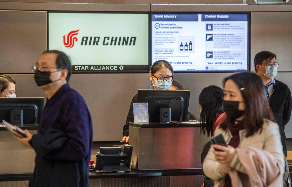 Chinese citizens wear face masks to protect against the spread of the Coronavirus as they check in to their Air China flight to Beijing, at Los Angeles International Airport, California, on February 2, 2020. AFP / Mark Ralston 