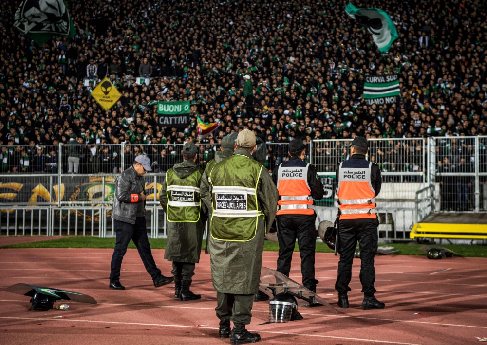 Moroccan security forces stand on guard as supporters of Raja Club Athletic chant slogans and wave their flags as they attend a Moroccan Botola football match between Raja and Mouloudia Oujda in Casablanca on January 22, 2020. AFP / Fadel Senna 
 