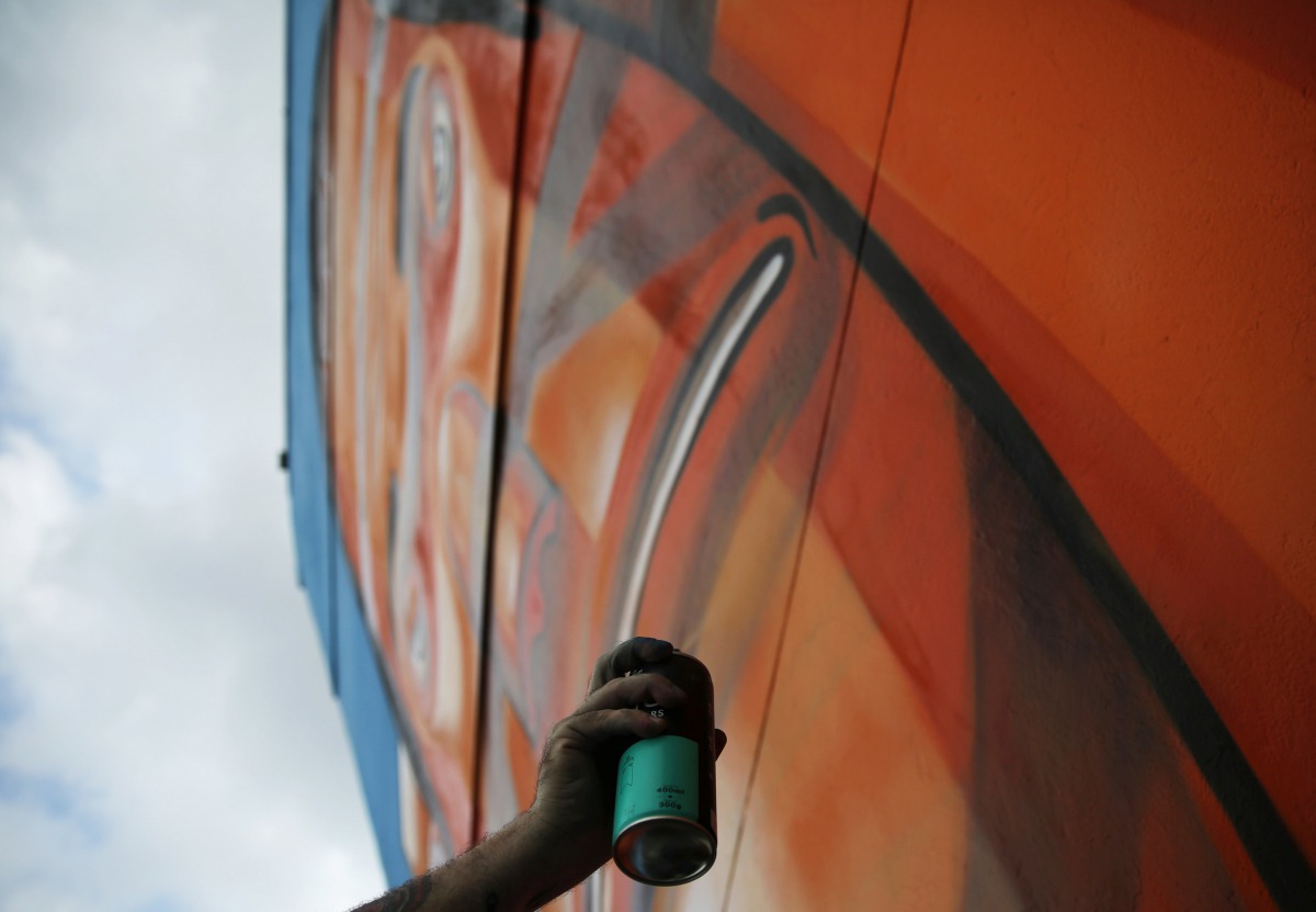 Brazilian artist Marcelo Eco works on a mural depicting indigenous people in protest against the construction of hydroelectric power plants in the Amazon rainforest in Rio de Janeiro, August 7, 2016. Reuters 