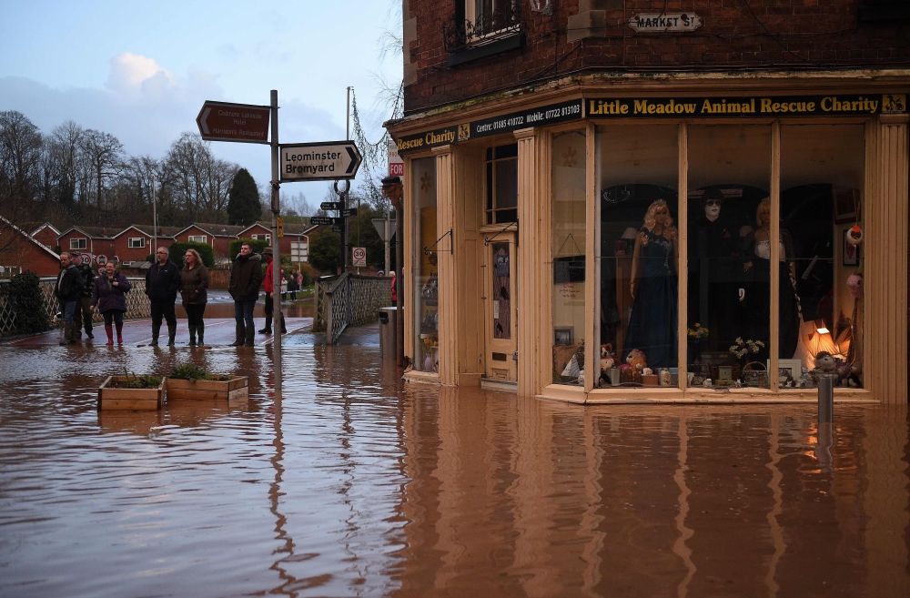 People look at flood water in Market Street in Tenbury Wells, after the River Teme burst its banks in western England, on February 16, 2020. AFP / Oli SCARFF