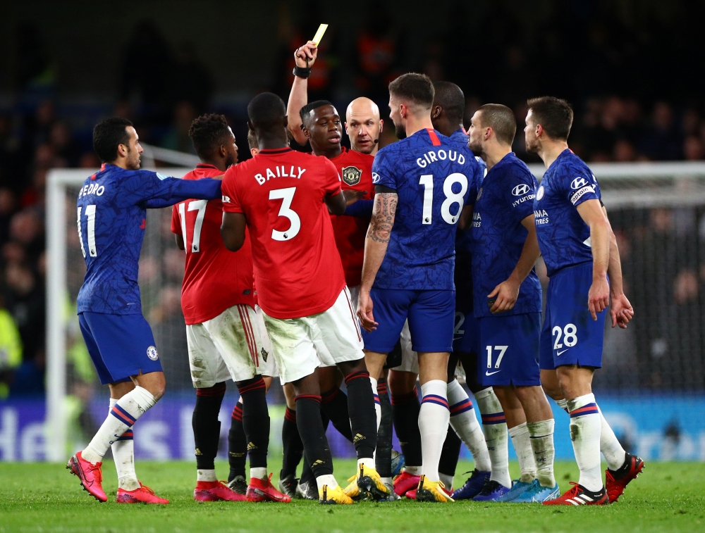 Manchester United's Aaron Wan-Bissaka is shown a yellow card by referee Anthony Taylor as Chelsea's Mateo Kovacic, Cesar Azpilicueta and teammates react REUTERS/Hannah McKay