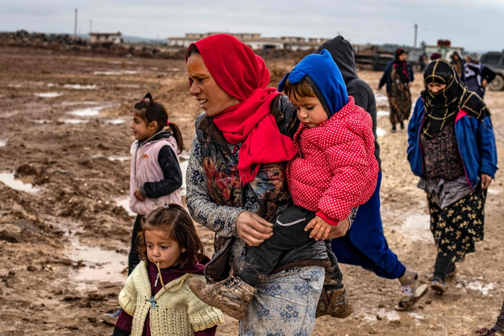 Syrian women accompany children in a muddy field in the Washukanni Camp for the internally displaced, near the predominantly Kurdish city of Hasakeh in northeastern Syria, on February 17, 2020. AFP / Delil Souleiman 