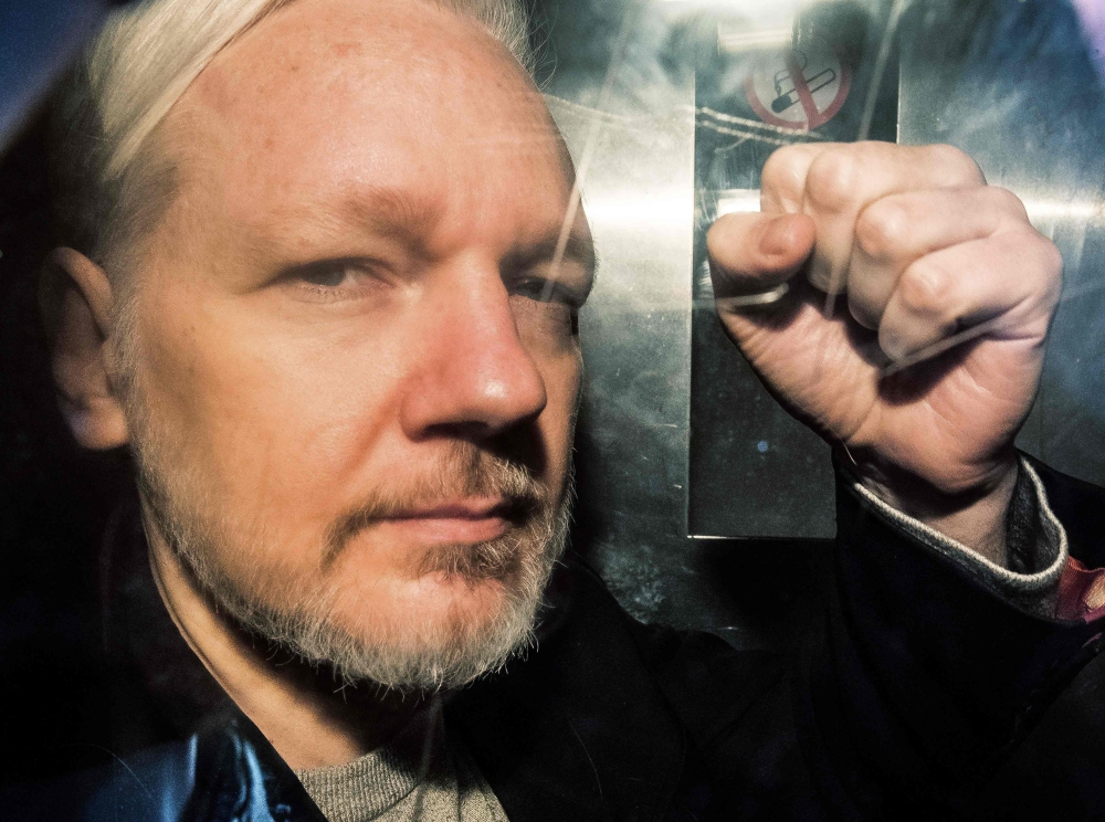Julian Assange gestures from the window of a prison van as he is driven out of Southwark Crown Court in London on May 01, 2019. AFP / Daniel Leal-Olivas