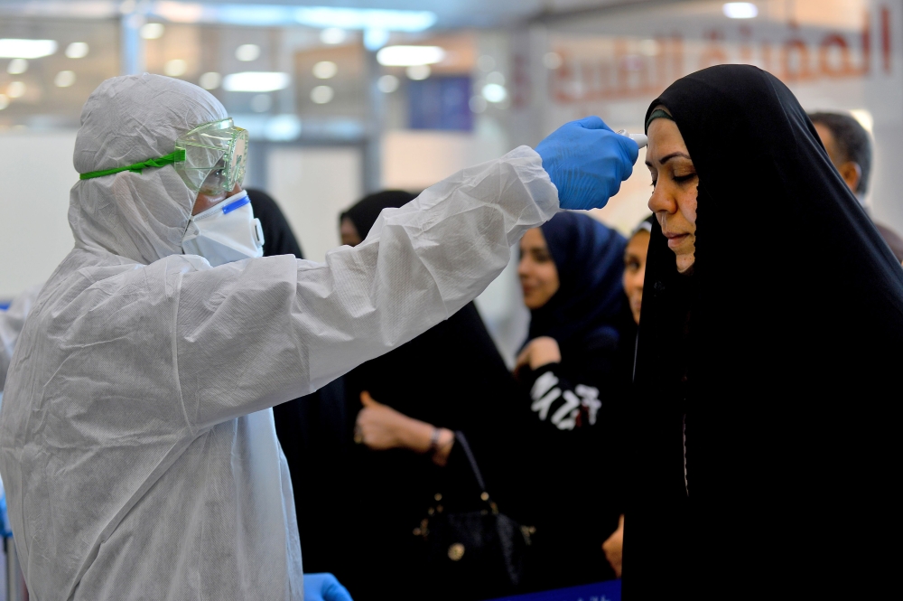 The body temperature of an Iraqi woman returning from Iran is measured upon her arrival at the Najaf International Airport on February 21, 2020, after Iran announced cases of coronavirus infections in the Islamic republic. / AFP / Haidar HAMDANI