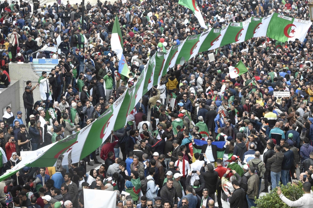 Algerian protesters march national flags during their weekly anti-government demonstration in the capital Algiers, on February 21, 2020. / AFP / RYAD KRAMDI