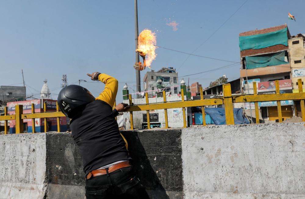 A man supporting a new citizenship law throws a petrol bomb at a Muslim shrine during a clash with those opposing the law in New Delhi India, February 24, 2020. Reuters/Danish Siddiqui
 