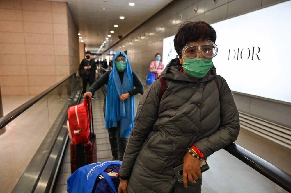 A passenger wearing a protective face mask and glasses arrives at Pudong International Airport in Shanghai, on February 24, 2020. AFP / Hector Retamal