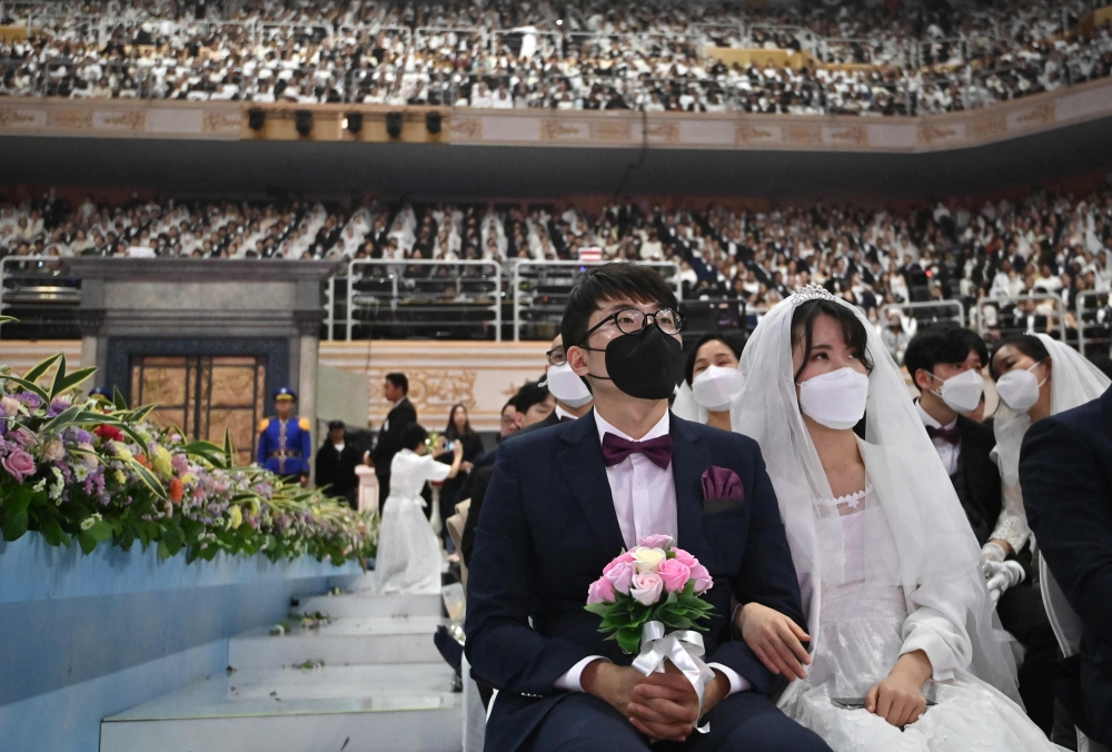 Couples wearing protective face masks attend a mass wedding ceremony organised by the Unification Church at Cheongshim Peace World Center in Gapyeong on February 7, 2020. AFP / Jung Yeon-je