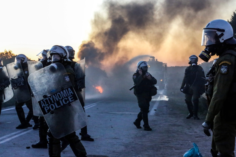 Riot police walk on a road near the town of Madamados as demonstrators protesting against the construction of a new controversial migrant camp on the northeastern Aegean island of Lesbos, on February 25, 2020. AFP / Manolis Lagoutaris 