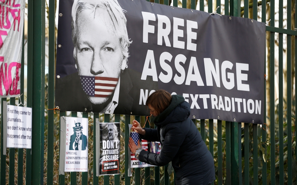 A supporter of WikiLeaks founder Julian Assange posts a sign on the Woolwich Crown Court fence, ahead of a hearing to decide whether Assange should be extradited to the United States, in London, Britain February 25, 2020. Reuters/Henry Nicholls 