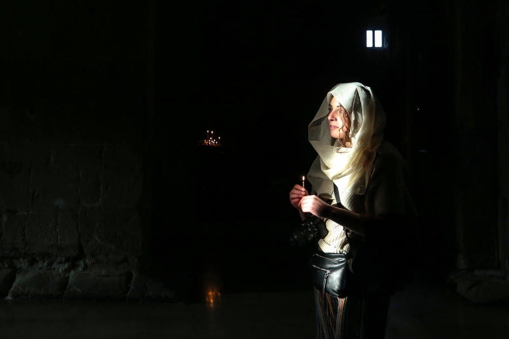 A woman holds a candle in Svetitshoveli Cathedral, an Orthodox Christian cathedral located in the historic town of Mtskheta, in Tbilisi, Georgia on February 19, 2020. (Özkan Bilgin / Anadolu Agency)
 