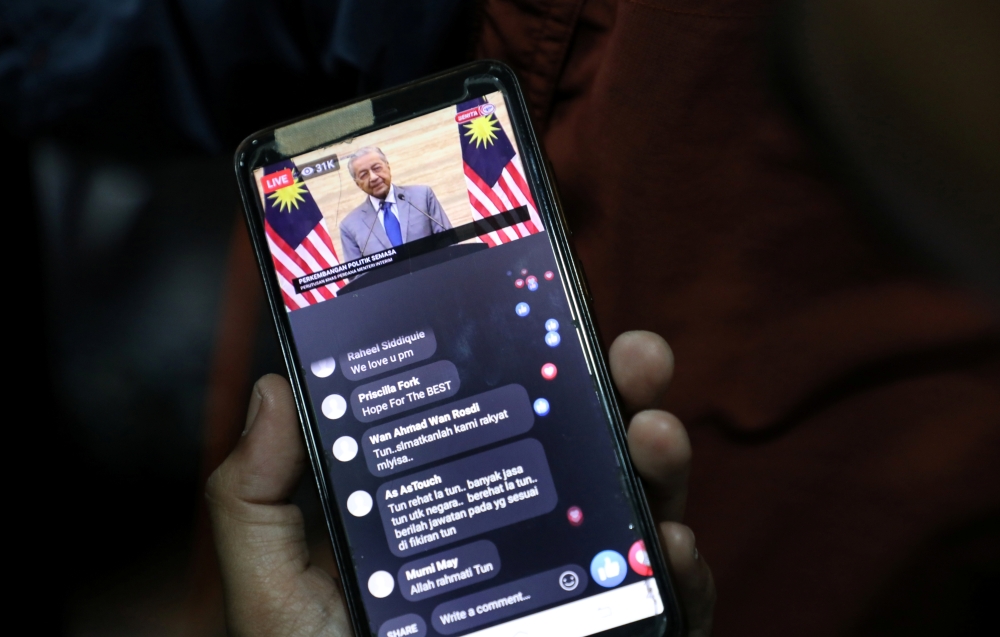A reporter watches Malaysian Interim Prime Minister Mahathir Mohamad news conference before a news conference in Petaling Jaya, Malaysia, February 26, 2020. REUTERS/Lim Huey Teng
