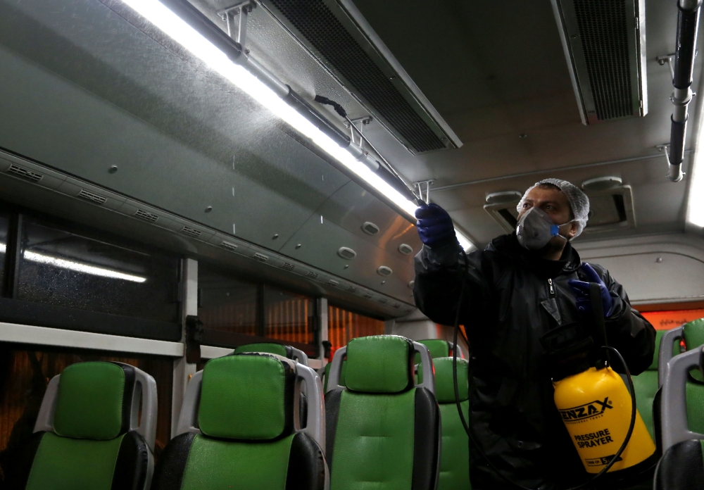 A Tehran Municipality worker cleans a bus to avoid the spread of the COVID-19 illness on February 26, 2020. AFP / ATTA KENARE