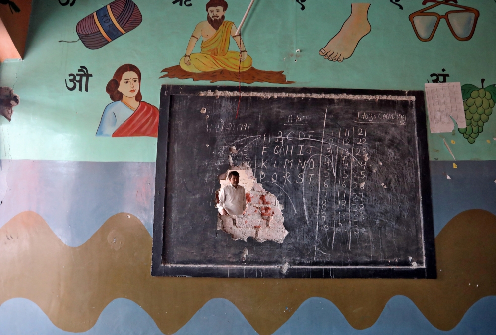 A man is seen through a hole on a classroom wall after the school building was attacked by a mob in a riot affected area following clashes between people demonstrating for and against a new citizenship law in New Delhi, India, February 27, 2020. REUTERS/R