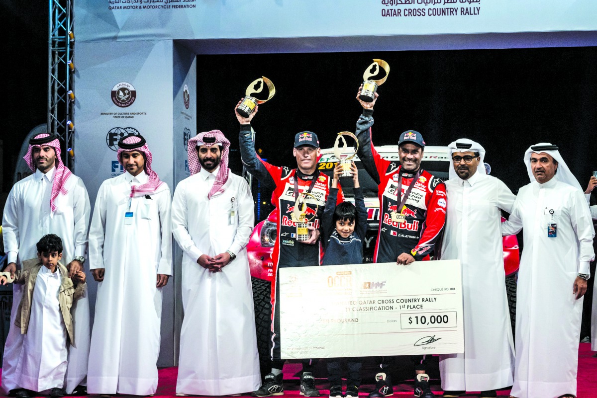Nasser Saleh Al Attiyah (third right) and his French co-driver Matthieu Baumel lift their trophies in the presence of QMMF President, Abdul Rahman Al Mannai yesterday.  