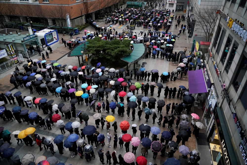 People wearing masks after the coronavirus outbreak wait in a line to buy masks as it rains in front of a department store in Seoul, South Korea, February 28, 2020. REUTERS/Kim Hong-Ji
