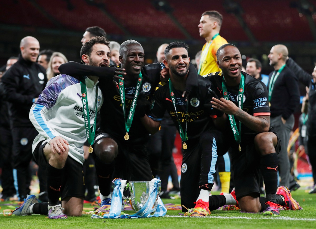 Manchester City's Bernardo Silva, Benjamin Mendy, Riyad Mahrez and Raheem Sterling pose with the trophy as they celebrate after winning the Carabao Cup. Action Images via Reuters/Matthew Childs 