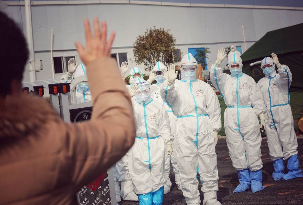 Medical staff members wave to a recovered patient (foreground L) at Leishenshan Hospital, the makeshift hospital for the COVID-19 coronavirus patients, in Wuhan in China's central Hubei province on March 1, 2020. / AFP / STR 