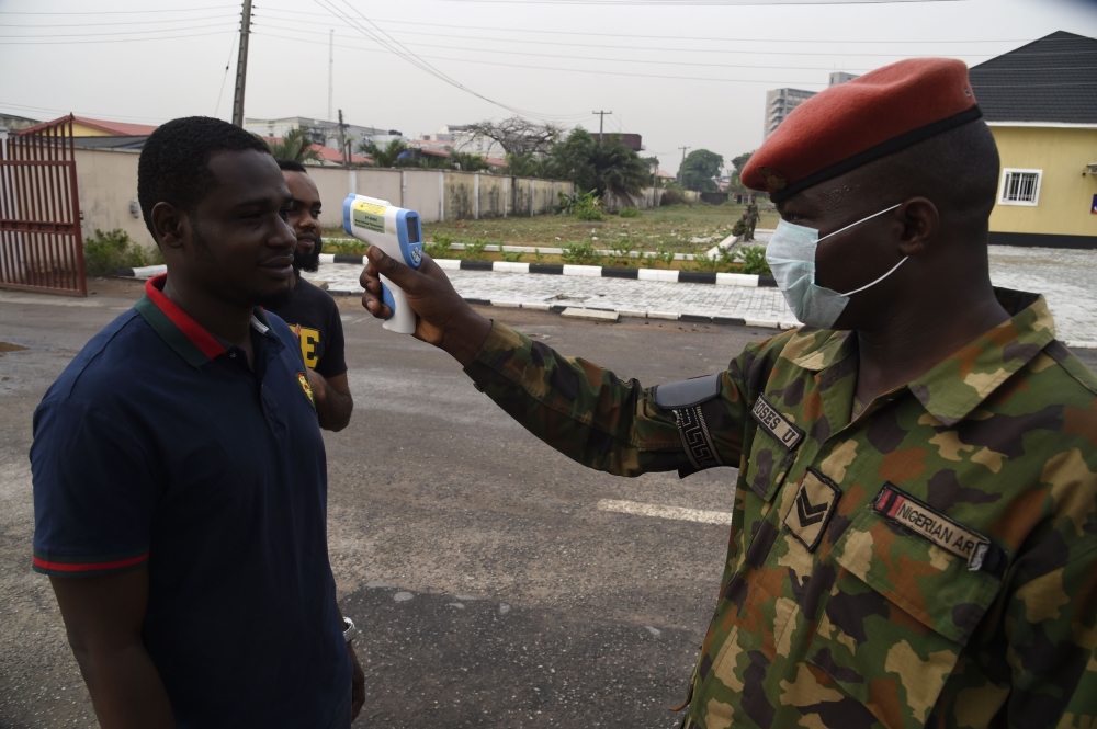 A soldier checks the body temperature of a visitor to the 68 Nigerian Army Reference Hospital at Yaba in Lagos, on February 28, 2020.  AFP / Pius Utomi Ekpei 
 