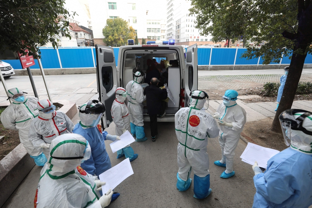  Medical staff assist a patient infected by the COVID-19 coronavirus leaving from Wuhan No.3 Hospital to travel to Huoshenshan Hospital in Wuhan in China's central Hubei province on March 4, 2020. / AFP / STR

