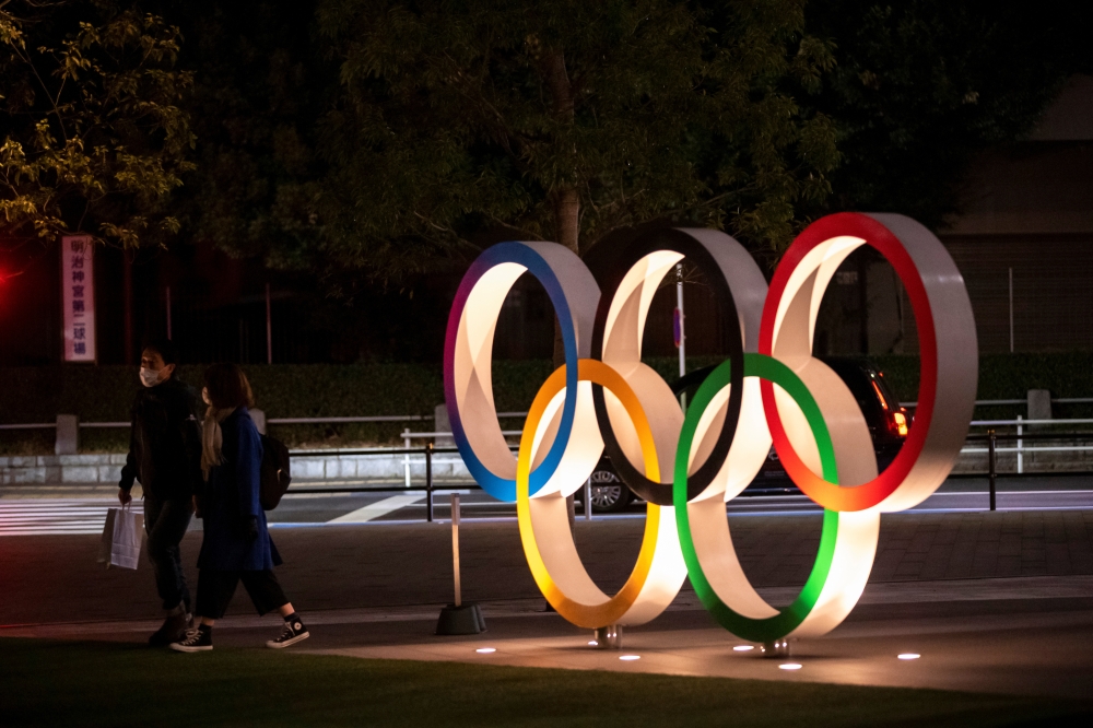  A couple wearing protective face masks, following the outbreak of the coronavirus, walk past The Olympic rings in front of the Japan Olympics Museum in Tokyo, Japan, March 3, 2020. REUTERS/Athit Perawongmetha 