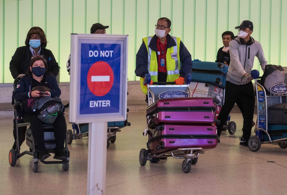Passengers wear face masks to protect against the COVID-19 (Coronavirus) after arriving at the LAX airport in Los Angeles, California on March 5, 2020. California has declared a state of emergency as the number of novel coronavirus cases and deaths in the