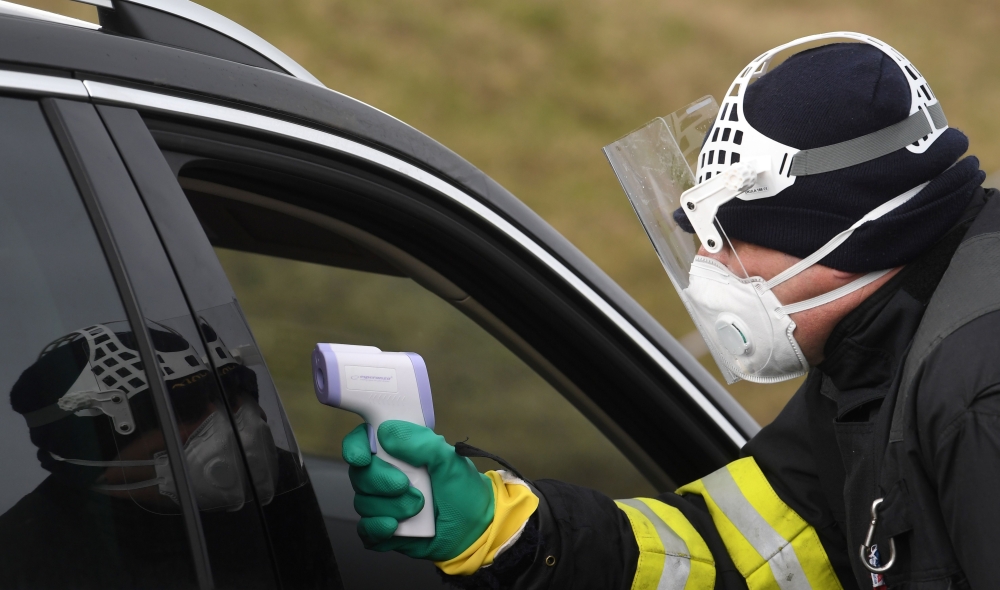A Czech police officer, with a protective mask, checks the temperature of a driver during sanitary checks on drivers at the border crossing between Germany and Czech Republic, near the German village of Furth and the Czech village Nova Kubice in a measure