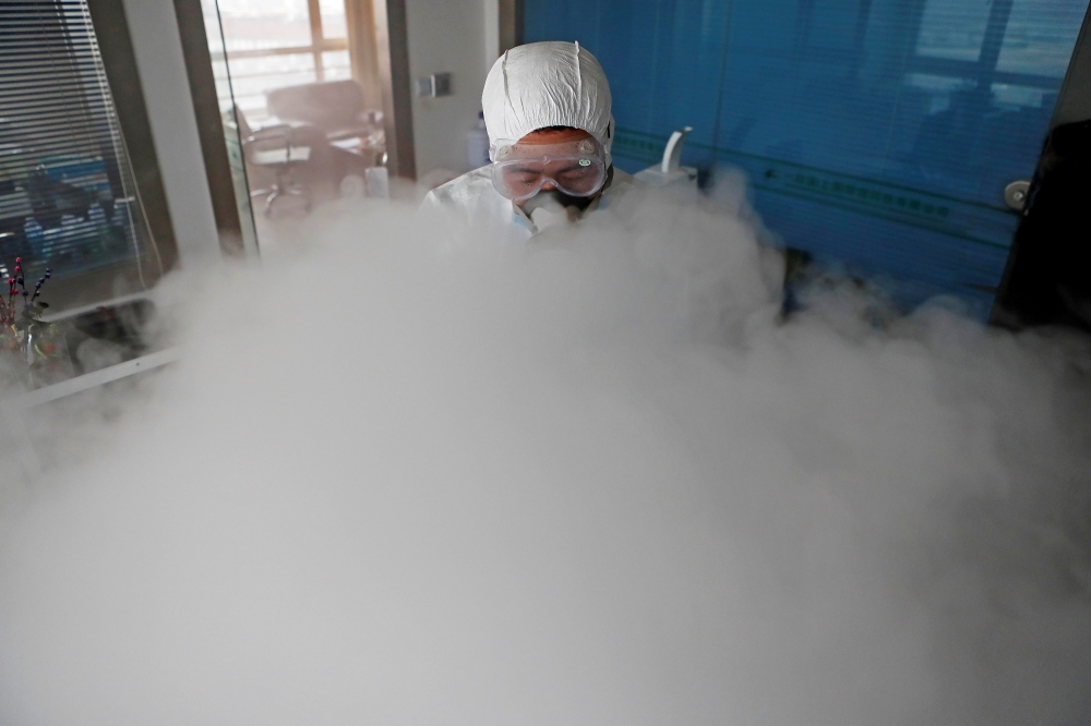 FILE PHOTO: A worker with sanitizing equipment disinfects an office following an outbreak of the coronavirus in the country, in Shanghai, China February 12, 2020. cnsphoto via REUTERS/File Photo 