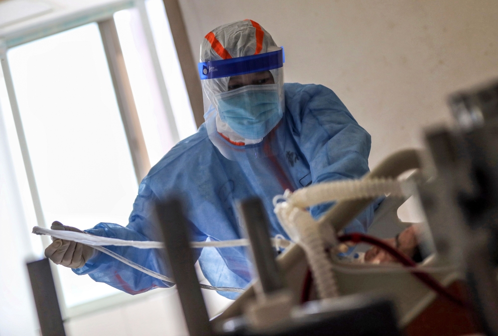 A medical staff member treats a patient infected by the COVID-19 coronavirus at Red Cross Hospital in Wuhan in China's central Hubei province on March 10, 2020.  AFP / STR