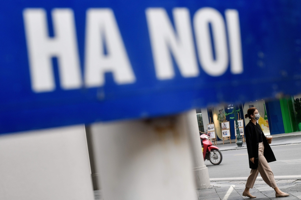 A woman, wearing a facemask amid fears of the spread of the COVID-19 novel coronavirus walks on a street in Hanoi on March 11, 2020. / AFP / Manan Vatsyayana 