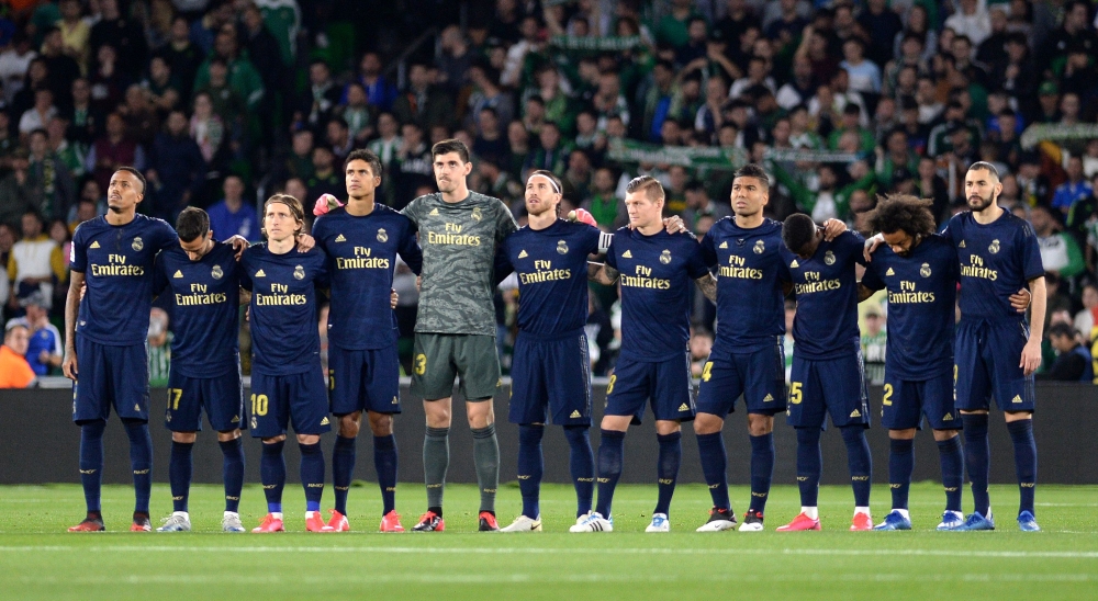 Real Madrid's players observe a minute of silence for former Betis player Manuel Regatero before the Spanish league football match between Real Betis and Real Madrid CF at the Benito Villamarin stadium in Seville on March 8, 2020. / AFP / CRISTINA QUICLER