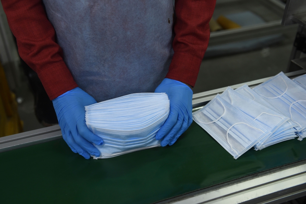An employee wearing a facemask amid concerns of the spread of the COVID-19 coronavirus works at the production line of facemasks at Salus Products, a manufacturer of surgical disposable products, on the outskirts of Ahmedabad on March 12, 2020. AFP / Sam 