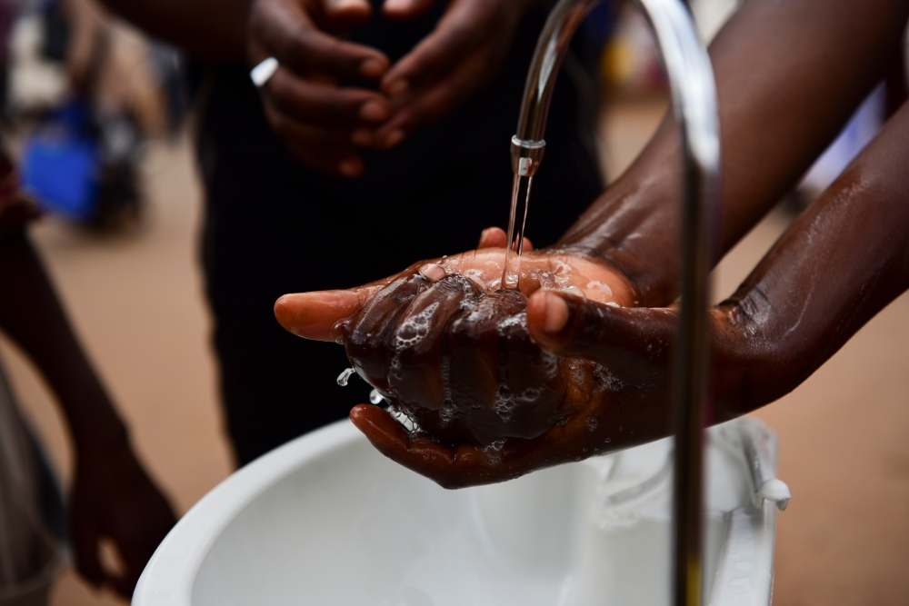 A passenger washes his hands at a public hand washing station before boarding a bus as a cautionary measure against the coronavirus at Nyabugogo Bus Park in Kigali, Rwanda. March 11, 2020. Reuters/Maggie Andresen