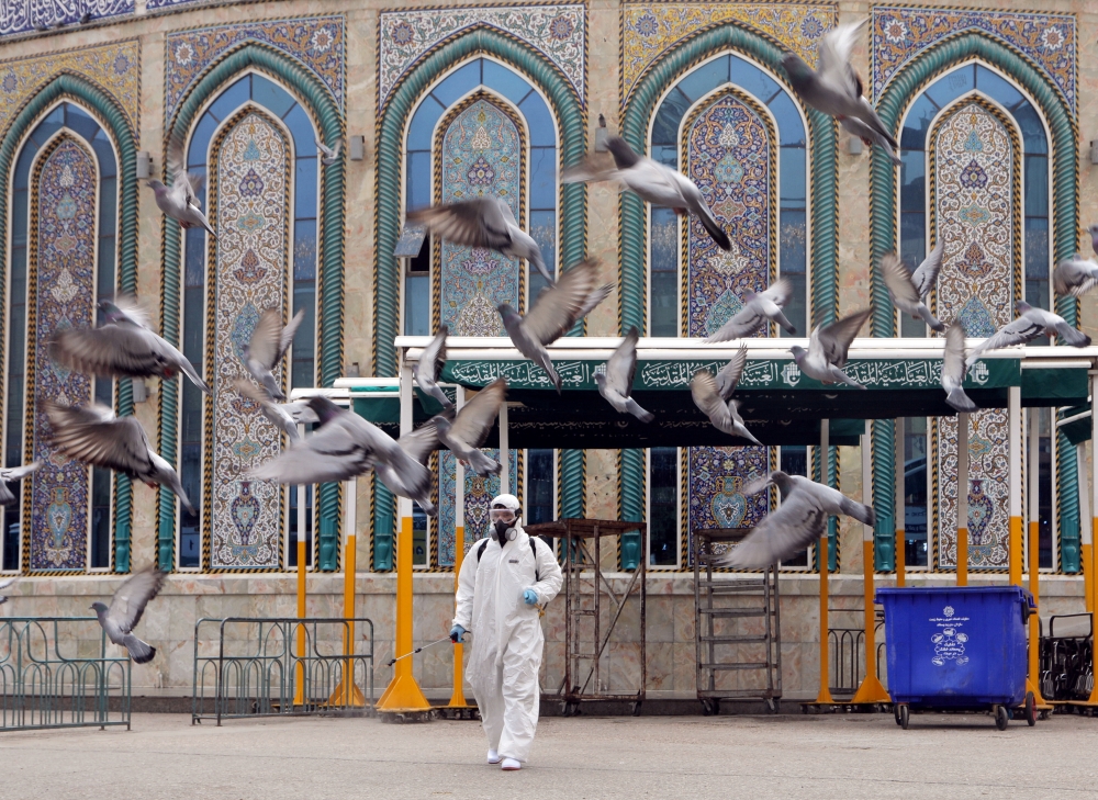 A worker in a protective suit sprays disinfectants near Imam Abbas shrine as a precaution against the coronavirus, following the outbreak, in the holy city of Kerbala, Iraq March 15, 2020.REUTERS/Abdullah Dhiaa Al-deen 