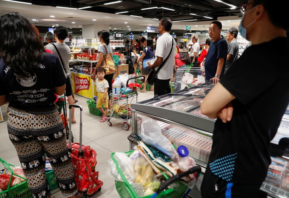 People buy food at a supermarket amid fears of a disruption in supplies after Malaysia announced the closure of its borders following the coronavirus outbreak in Singapore, March 17, 2020. REUTERS/Edgar Su