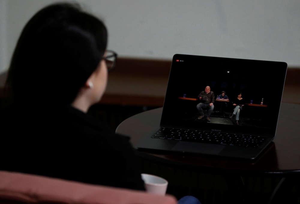 A woman waches the live stream of the performance of the 'First Hungarian Quarantine Theatre' in Budapest, Hungary, March 16, 2020. Picture taken March 16, 2020. REUTERS/Bernadett Szabo