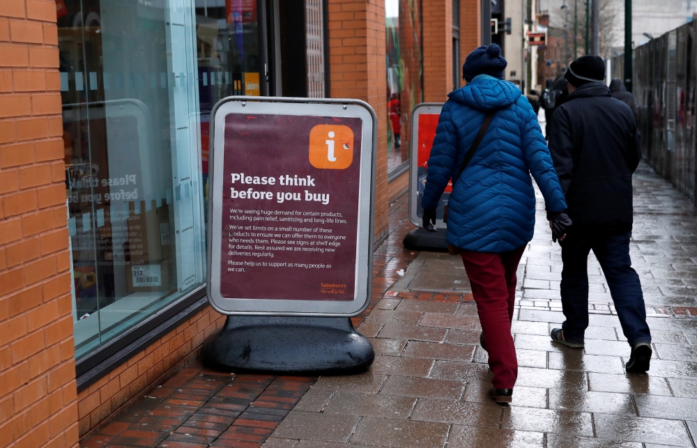 People walk past a sign warning customers of product shortages outside a Sainsbury's Local supermarket in central Birmingham, Britain, March 15, 2020 . REUTERS/Andrew Boyers